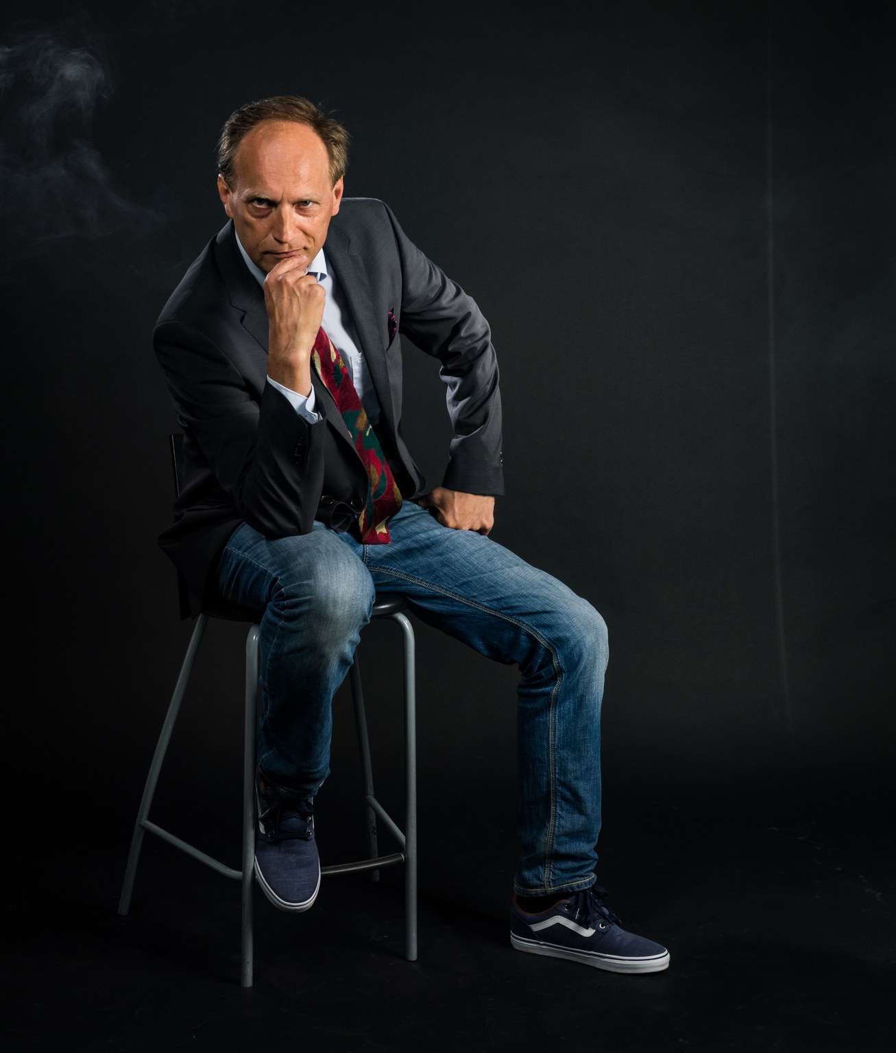 Janne Oravisto istuu korkealla jakkaralla käsi leuan alla